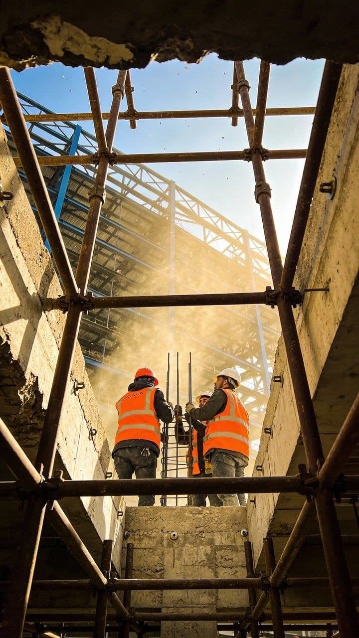 Construction workers in orange hi-vis on scaffolding at a live project